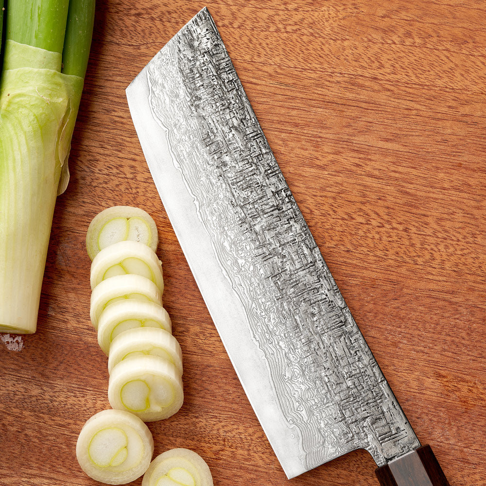 Sliced leeks and a Damascus steel knife on a wooden surface