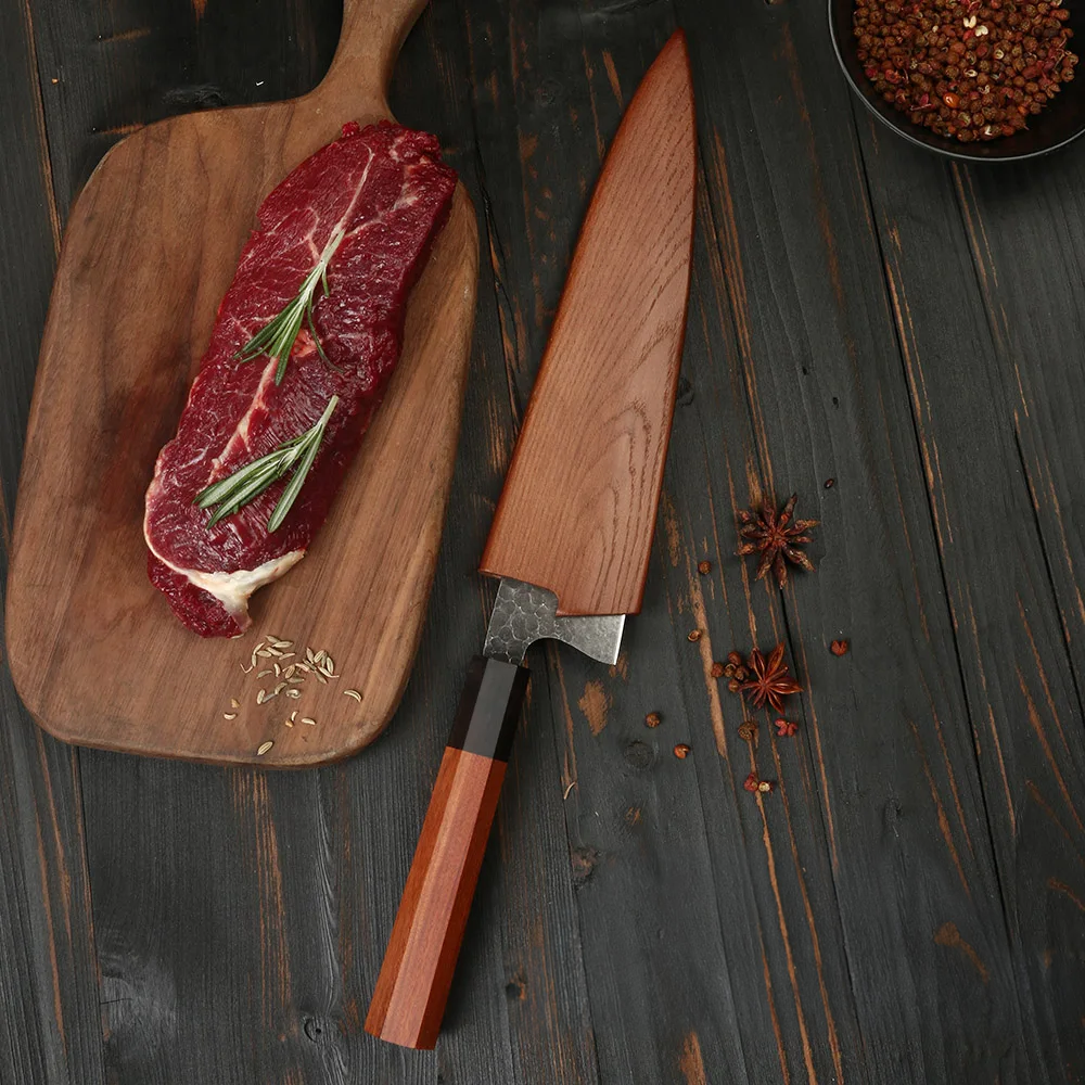 Chef Knife on wooden table near steak and condiments