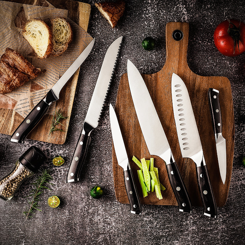 Set of german steel sharp and premium knives on a wooden cutting board with bread and vegetables on a dark surface