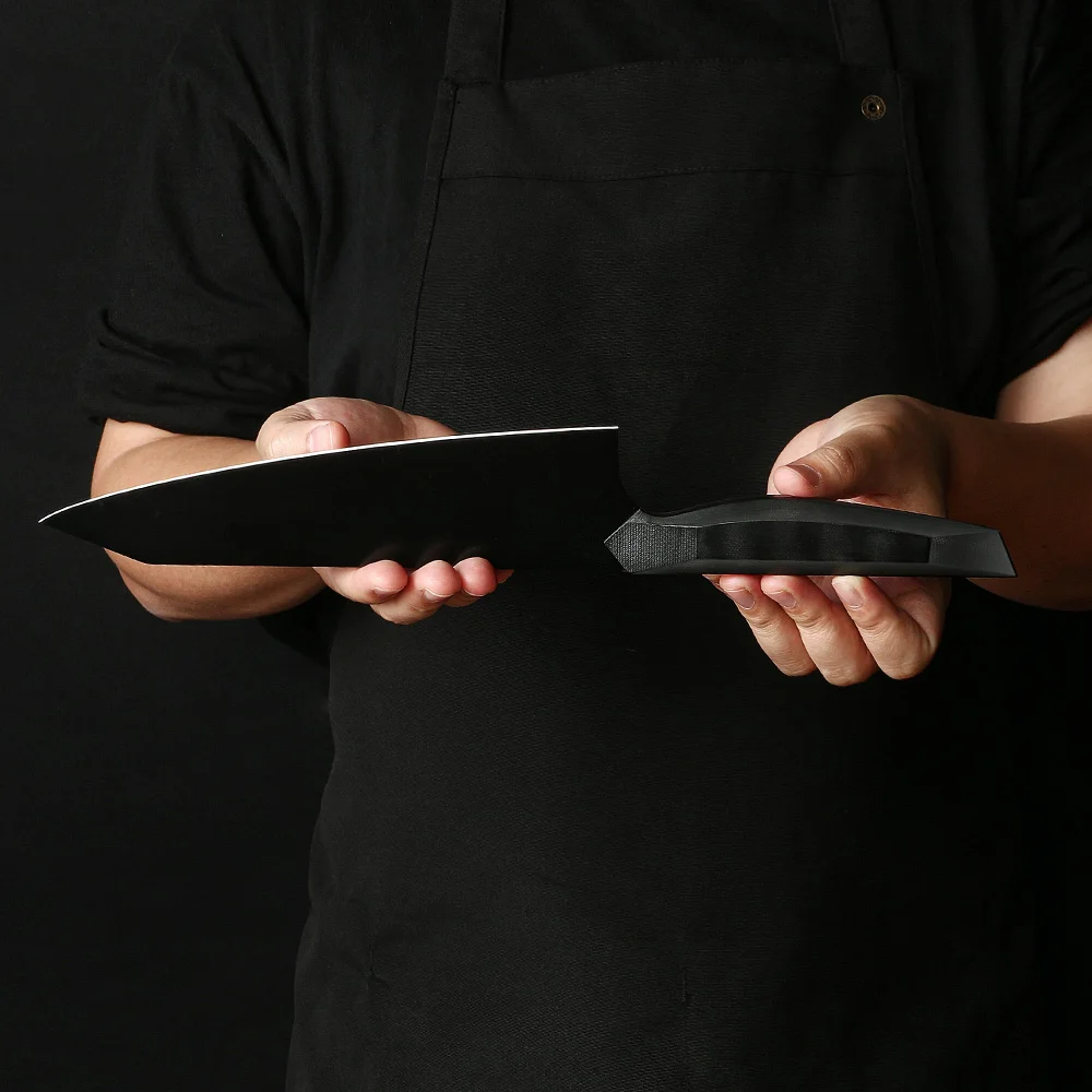 Professional chef holds japanese black knife prepared to dice and slice