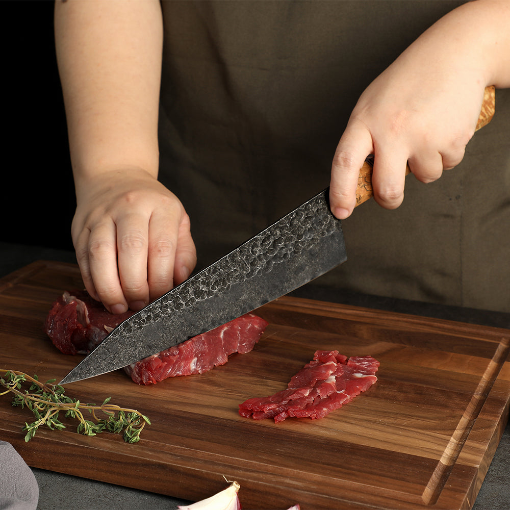 chef japonez taie steak cu un cutit profesional pe lemn