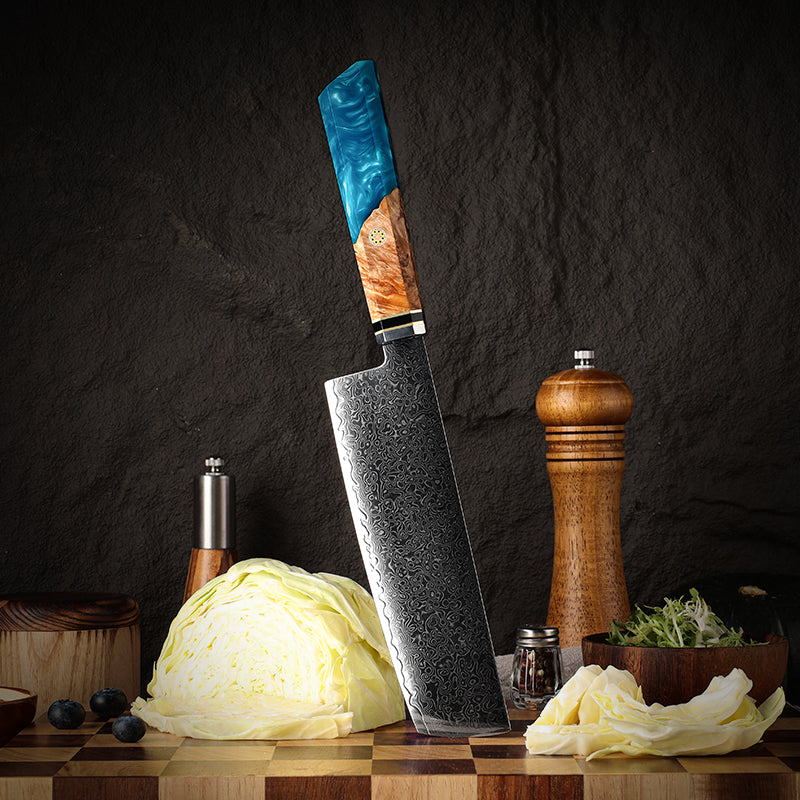 japanese nakiri knife with a decorative handle on a wooden cutting board with vegetables and a pepper grinder.