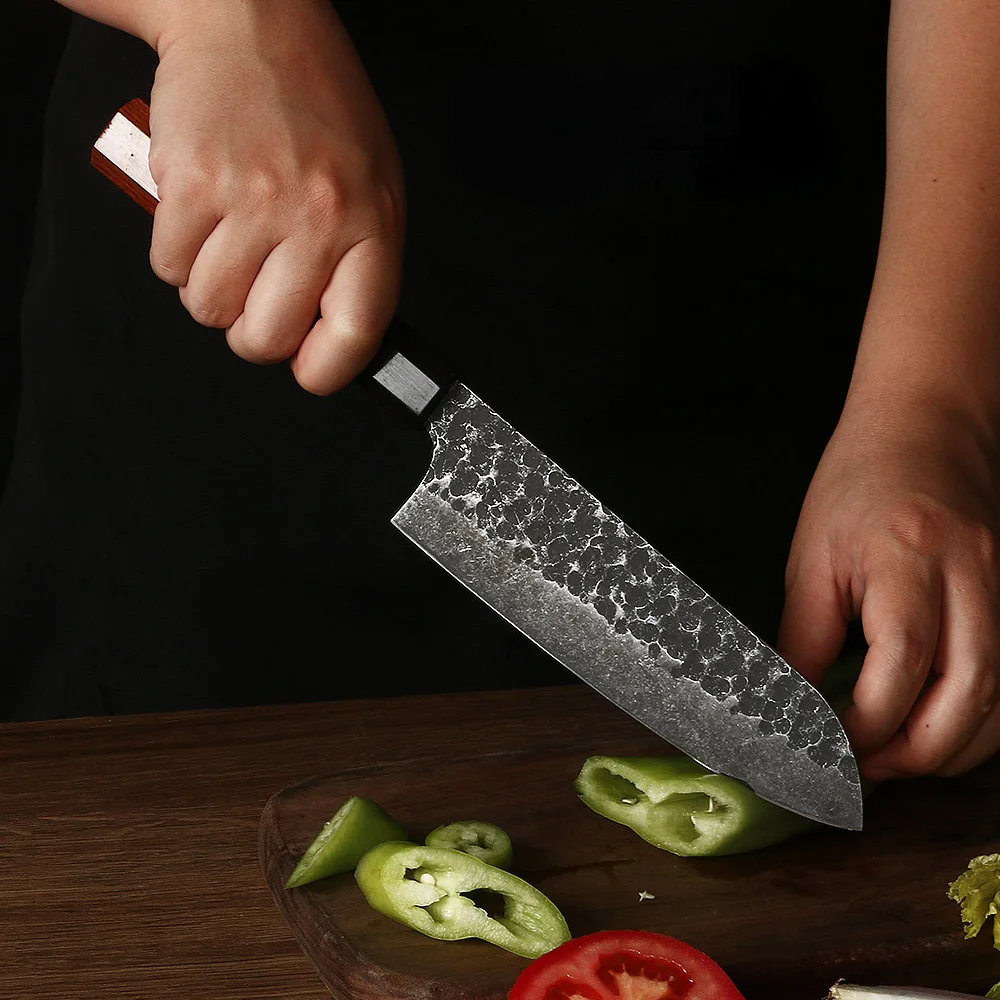 Santoku knife in the hands of a professional chef slicing peppers